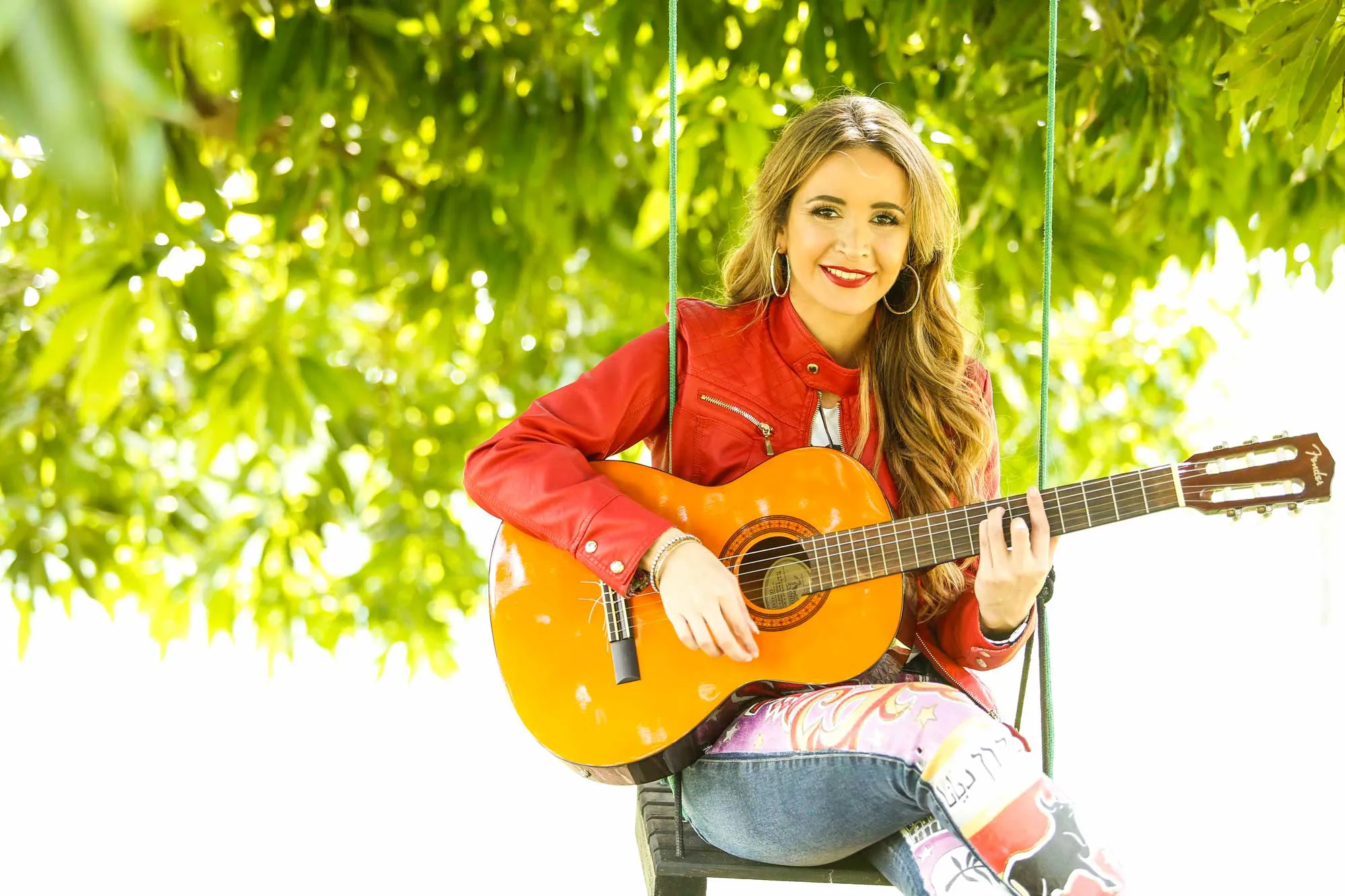 Daiana con guitarra en una hamaca bajo los árboles