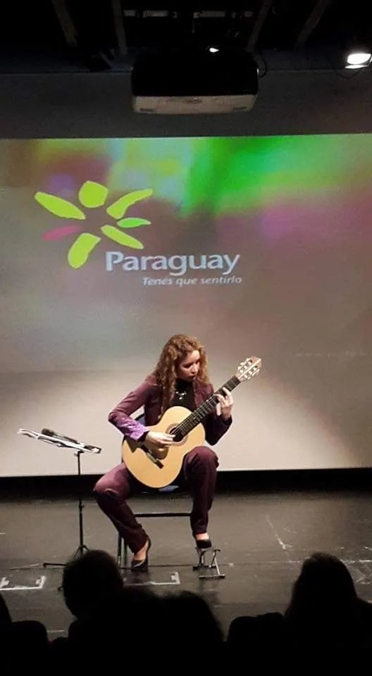 Daiana tocando ante una pantalla con la marca Paraguay