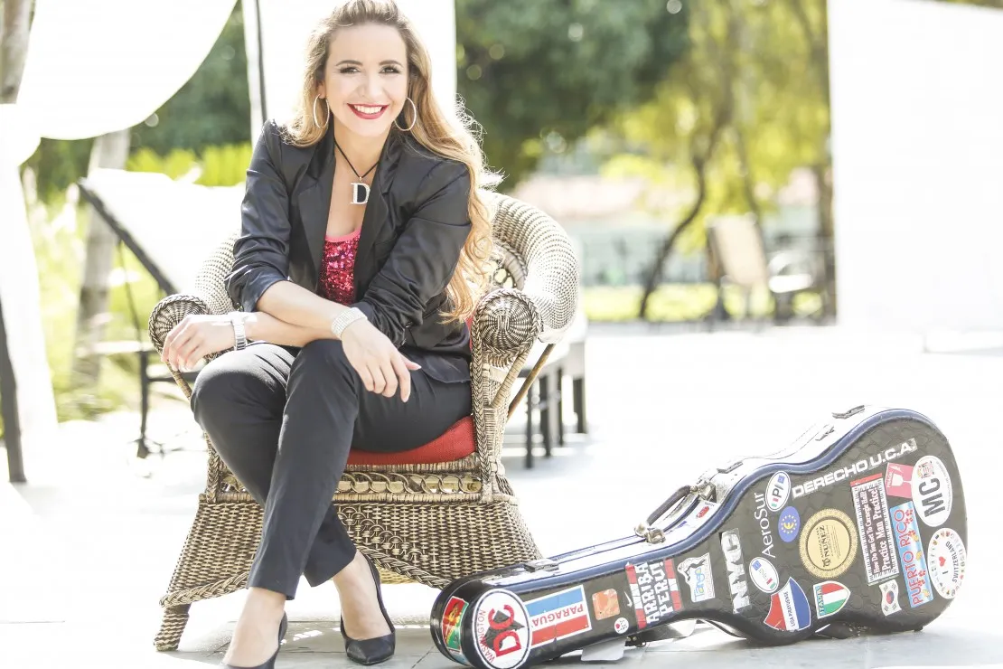 Daiana sentada en un sillón, estuche de guitarra en el piso